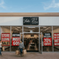 Exterior of a Saks Off 5th store at an outlet mall with red 'Store Closing' and 'Everything Must Go' signs.
